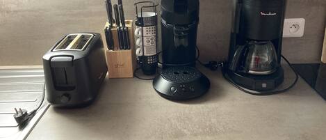 A kitchen counter with a toaster, a coffee maker, and a knife block.
