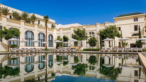 Ein Resort mit großem Pool, Liegestühlen und Palmen.