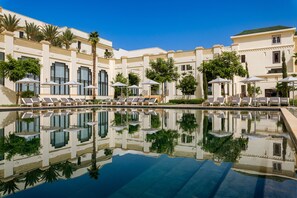 Un complexe hôtelier doté d’une grande piscine, de chaises longues et de palmiers.