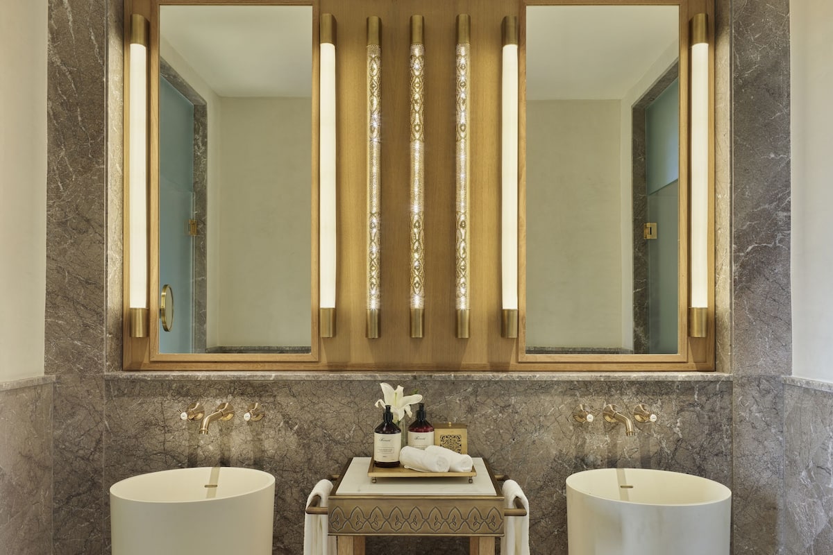 Une salle de bain avec deux lavabos, un grand miroir et un meuble-lavabo doté d’un porte-serviettes.