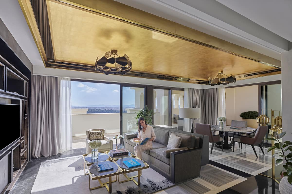 Une chambre d’hôtel moderne dotée d’un grand balcon, d’un canapé, d’une table basse et d’un coin repas.