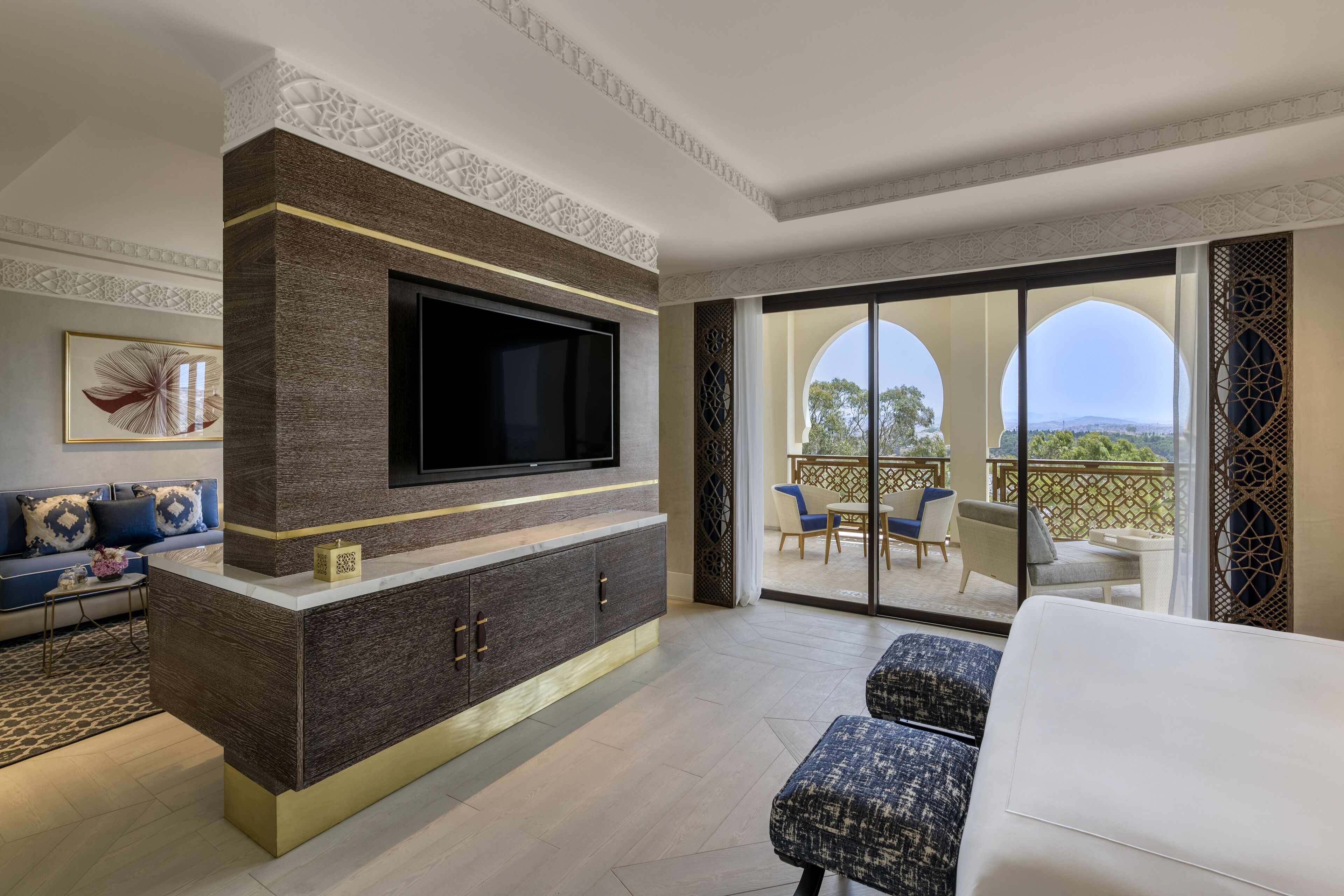 Una sala de estar moderna con un televisor de pantalla plana, un sofá y un balcón con mobiliario exterior.