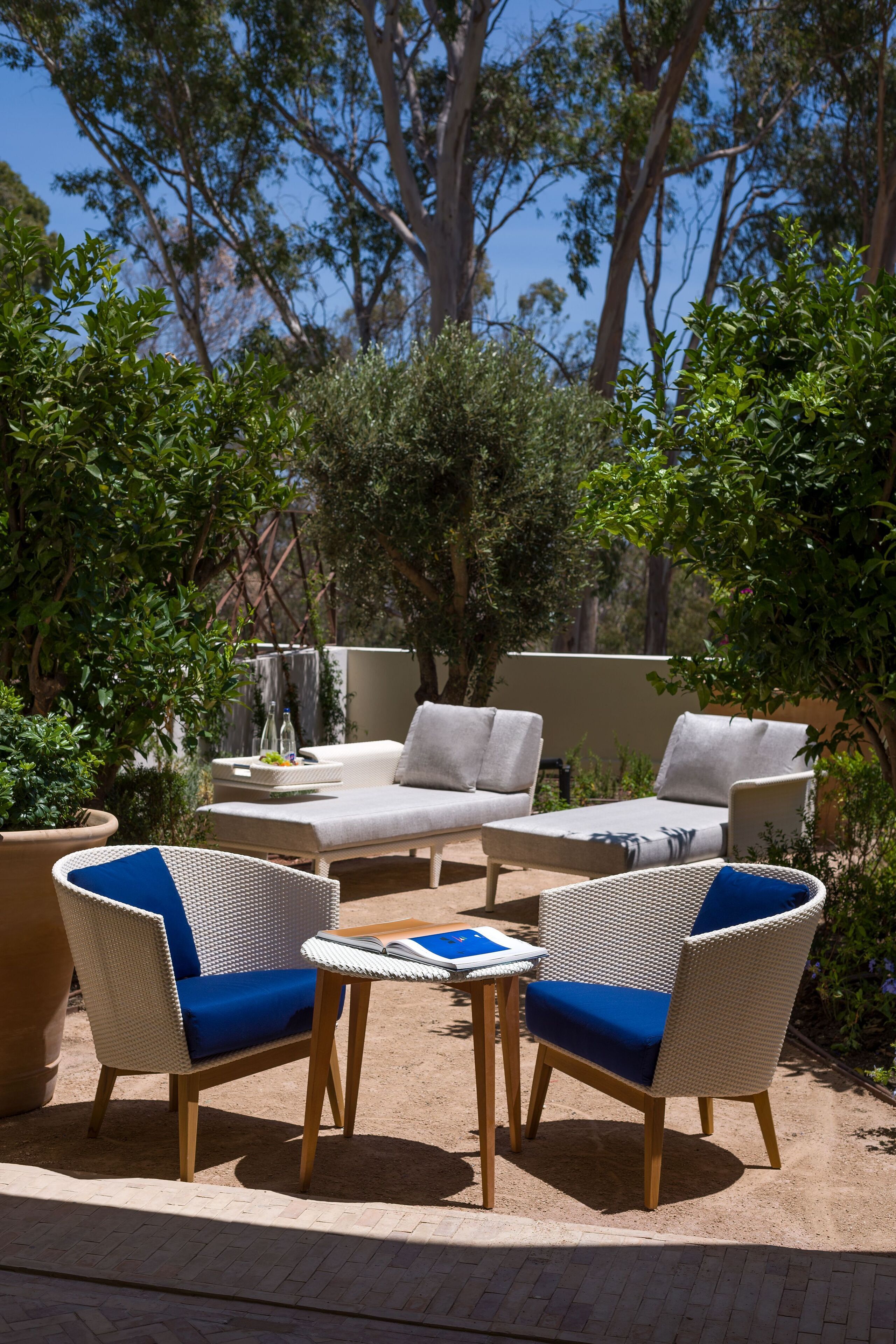 Un patio con mobiliario de mimbre, una pequeña mesa y plantas en macetas.
