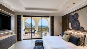 Une chambre d’hôtel moderne dotée d’un grand lit, d’une télévision à écran plat, d’un balcon avec coin salon extérieur et d’œuvres d’art décoratives sur les murs.