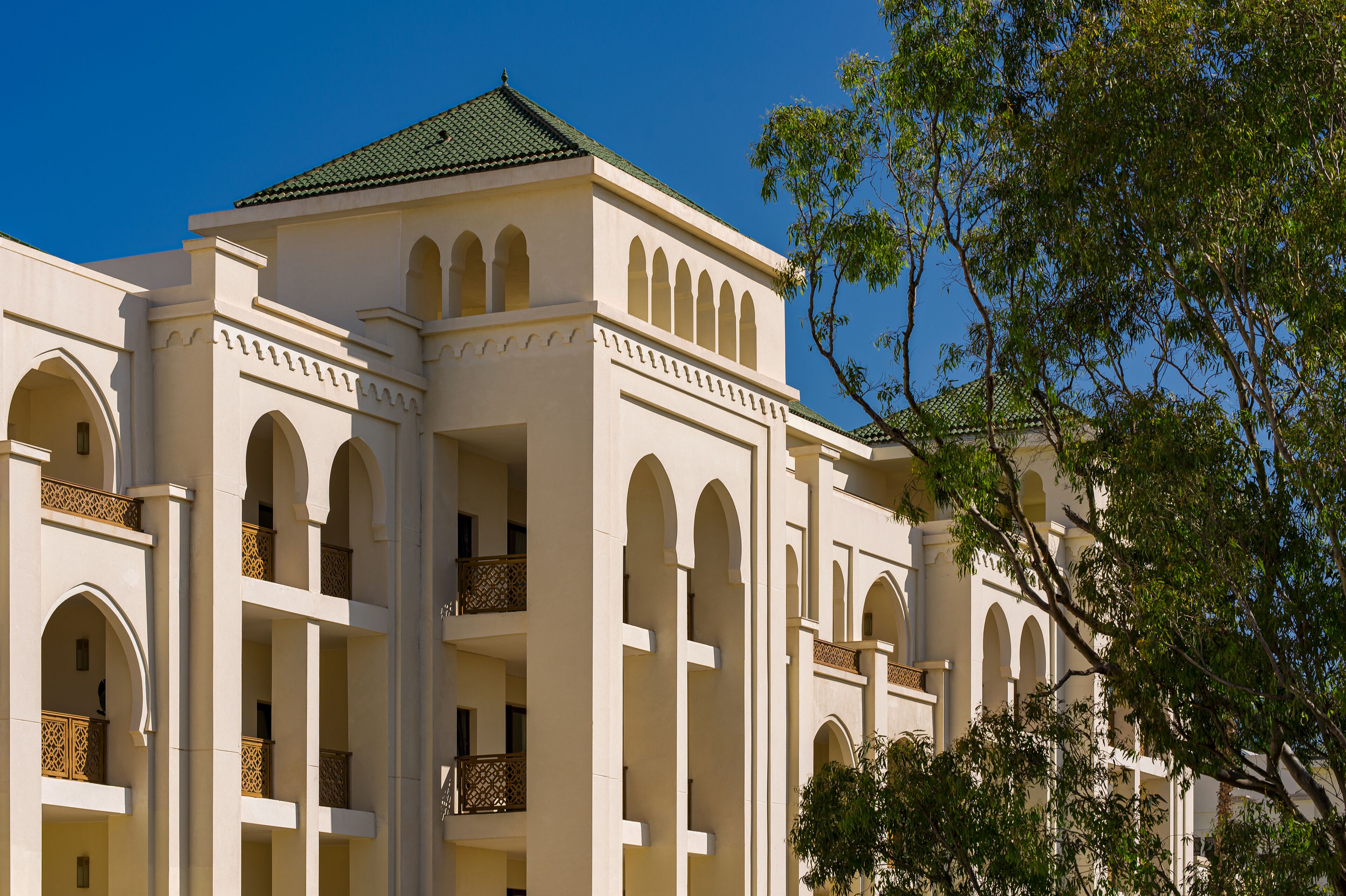 A multi-story building with arched balconies and a green roof.