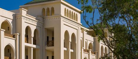 A multi-story building with arched balconies and a green roof.