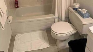 Een badkamer met een bad, toilet en een douchegordijn.