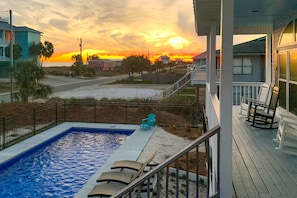 Relax by the pool surrounded by lush vegetation and a serene sunset view.