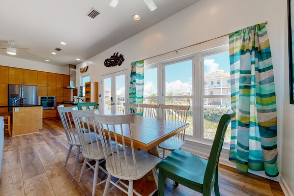 Enjoy meals in the kitchen with a view, featuring an oven, wooden cabinets, and a dining area with a wooden table and comfortable seating.