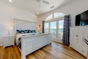Classic bedroom with a large bed, television, and wardrobe, offering a view of the outside.