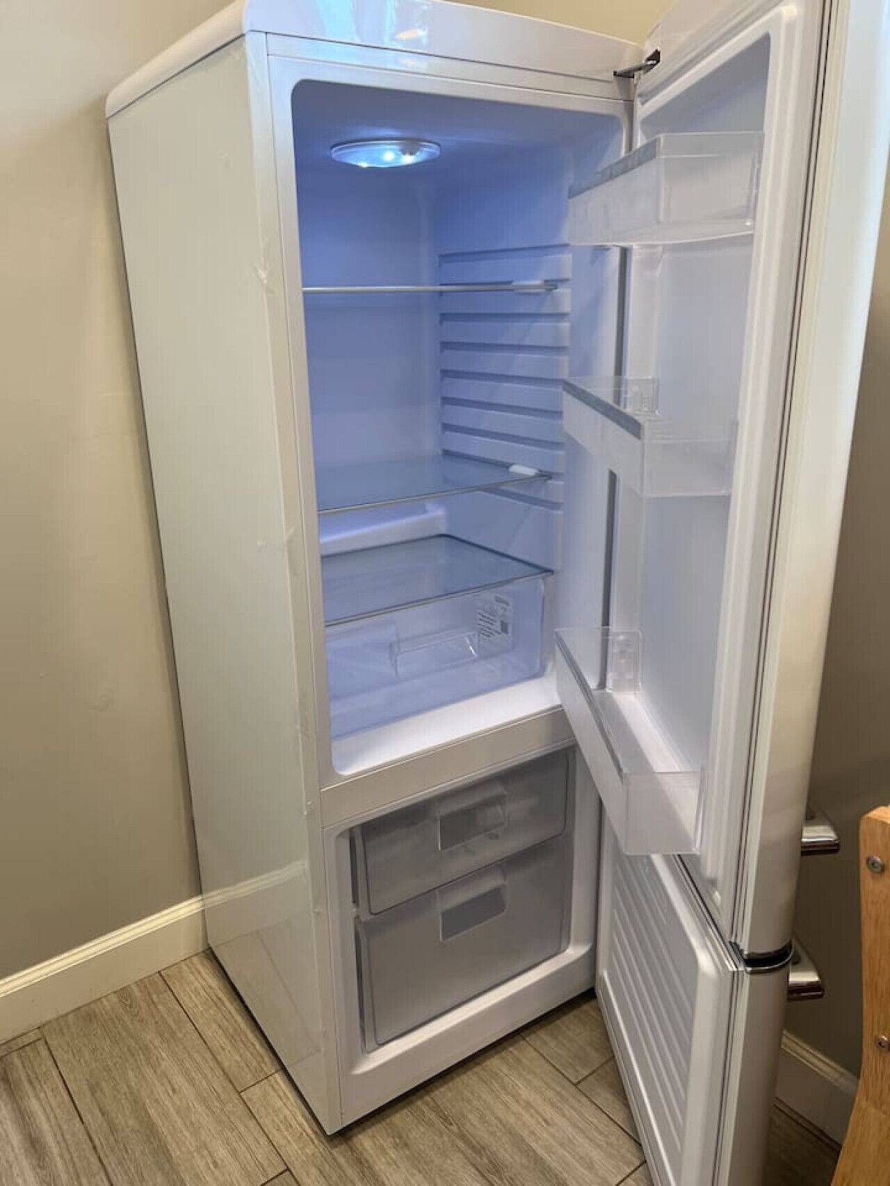 A compact refrigerator with a transparent door, a freezer compartment below, and a control panel on the right side.