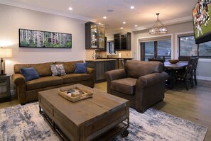 Una sala de estar con sofá, sillón, mesa de centro y televisor.