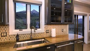 Una cocina con un ventanal grande, electrodomésticos de acero inoxidable y vistas a la montaña.