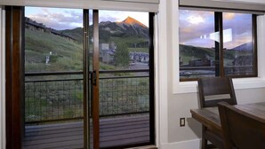 Una habitación con un gran ventanal corredero que da a un balcón con vistas a una montaña y edificios.