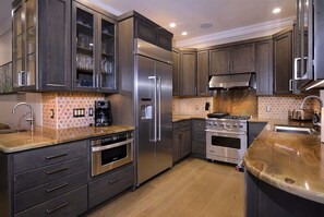 Una cocina moderna con electrodomésticos de acero inoxidable, armarios oscuros y salpicadero con diseño.