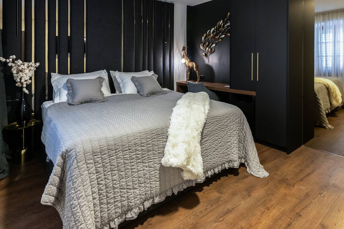 Une chambre moderne avec un grand lit, une armoire en bois foncé et un élément décoratif mural.