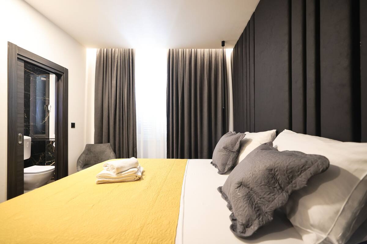 Une chambre d’hôtel avec un lit, des rideaux, une salle de bain et une porte.
