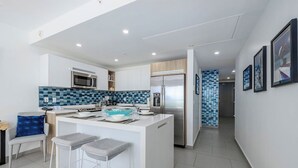 Una cocina moderna con una isla central, taburetes de bar y un microondas.