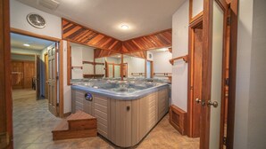 A bathroom with a large, freestanding bathtub, wooden ceiling, and a clock on the wall. - Enclave 43 (Keystone)