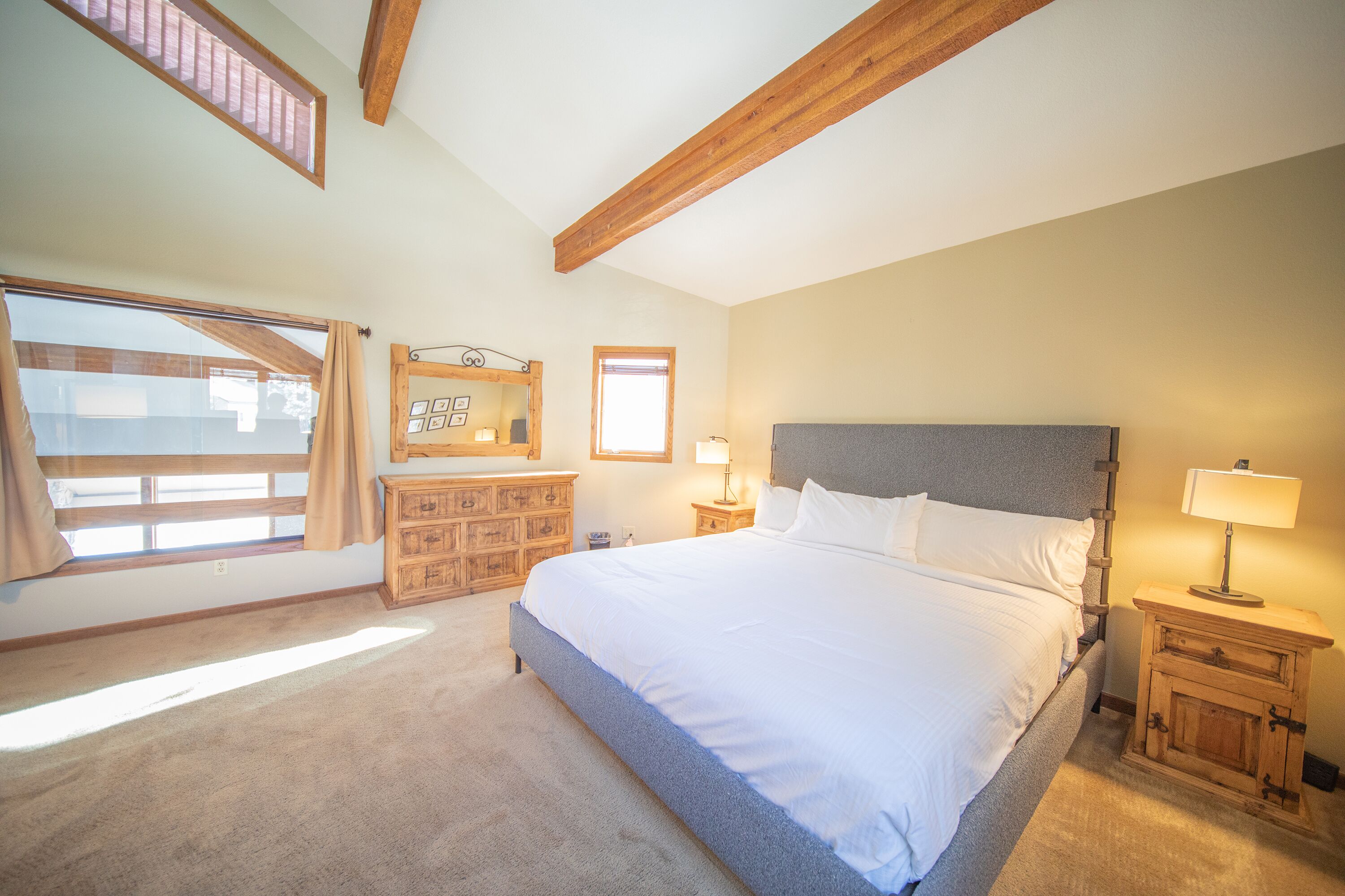 Une chambre à coucher avec un grand lit, une tête de lit en bois, une commode et une table de chevet avec une lampe.