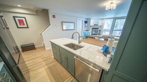 A modern kitchen with a built-in dishwasher, a stainless steel sink, and a marble countertop. - Liftside 304 (Keystone)