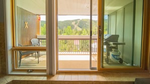 A room with a sliding glass door leading to a balcony with a view of a forested hillside. - Liftside 304 (Keystone)