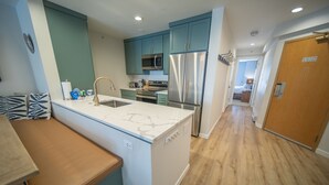 A modern kitchen with teal cabinets, stainless steel appliances, and a marble countertop. - Liftside 304 (Keystone)
