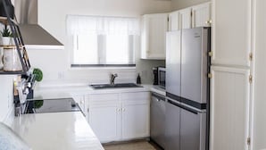A modern kitchen with white cabinets, stainless steel appliances, and a large island. - The Hillview Hangout (Grand Junction)
