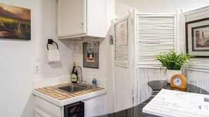 A compact kitchen with a sink, wine glasses, a bottle, and a clock. - The Hillview Hangout (Grand Junction)