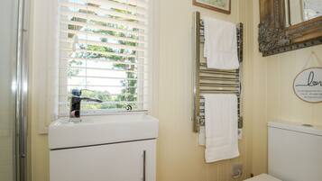 A bathroom with a window, a sink, a toilet, and a towel rack.