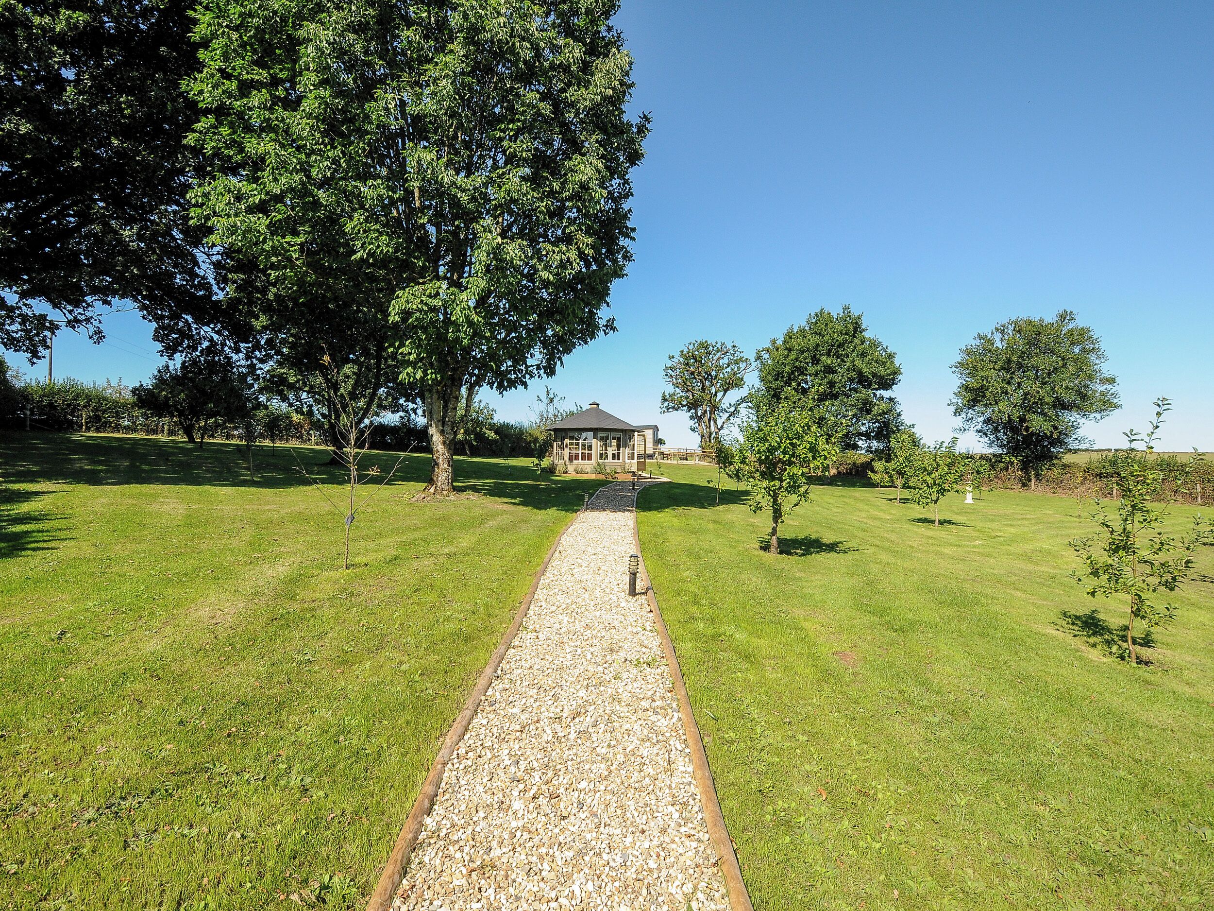 A pathway leading to a gazebo in a grassy area with trees.