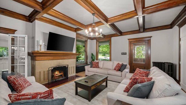 A spacious living room with a fireplace, a television, and a large window. - Historic Family Home with 8 BDRMS, 8 BATHS & 3 Kitchens! (Spokane)