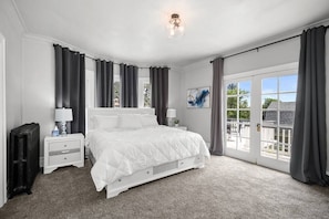 Una camera da letto con un letto grande, un comodino, una lampada e vista all'esterno tramite una porta scorrevole in vetro.