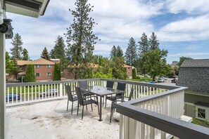 A balcony with a glass table and chairs, overlooking a residential area with houses and trees. - Historic Family Home with 8 BDRMS, 8 BATHS & 3 Kitchens! (Spokane)