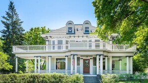 A two-story house with a porch, columns, and a flag. - Historic Family Home with 8 BDRMS, 8 BATHS & 3 Kitchens! (Spokane)