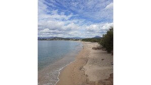 Ein Strand mit blauem Himmel und fernen Bergen.