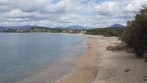 Une plage avec un ciel dégagé et des montagnes à l’horizon.