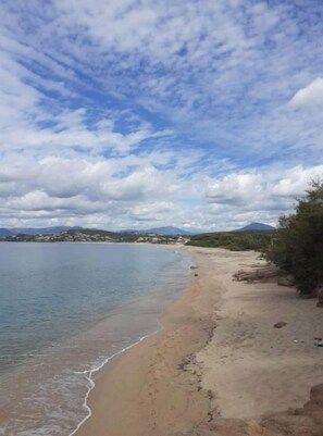 Una playa con cielos despejados y montañas a lo lejos.