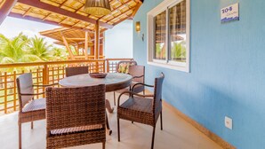 Un espace extérieur aménagé avec des meubles en osier, une table ronde et une vue sur les palmiers.