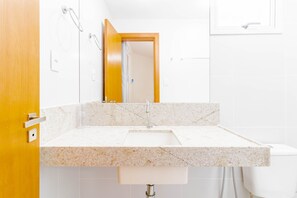 Une salle de bain avec un lavabo blanc, un miroir et une porte en bois.
