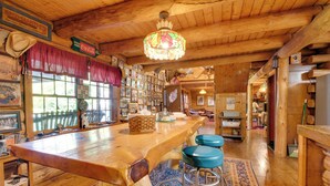Un interior rústico de madera con una mesa barra larga, taburetes de bar azules y una lámpara de araña.