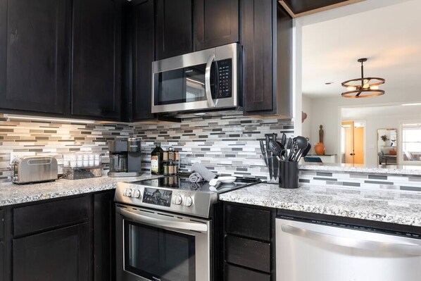 Modern kitchen with stainless steel appliances, granite countertop, and a backsplash of gray and white tiles.