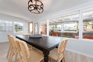 Enjoy meals in this dining area with a table and four chairs, surrounded by large windows offering a view of the landscaped outdoor space.