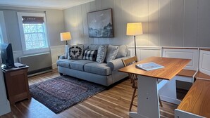 Ett modernt vardagsrum med en grå soffa, ett soffbord i trä och ett TV-bord.