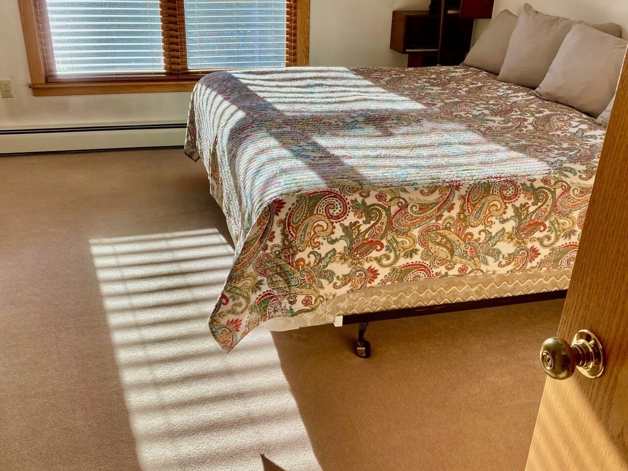 A bedroom with a bed, a window, and a door.