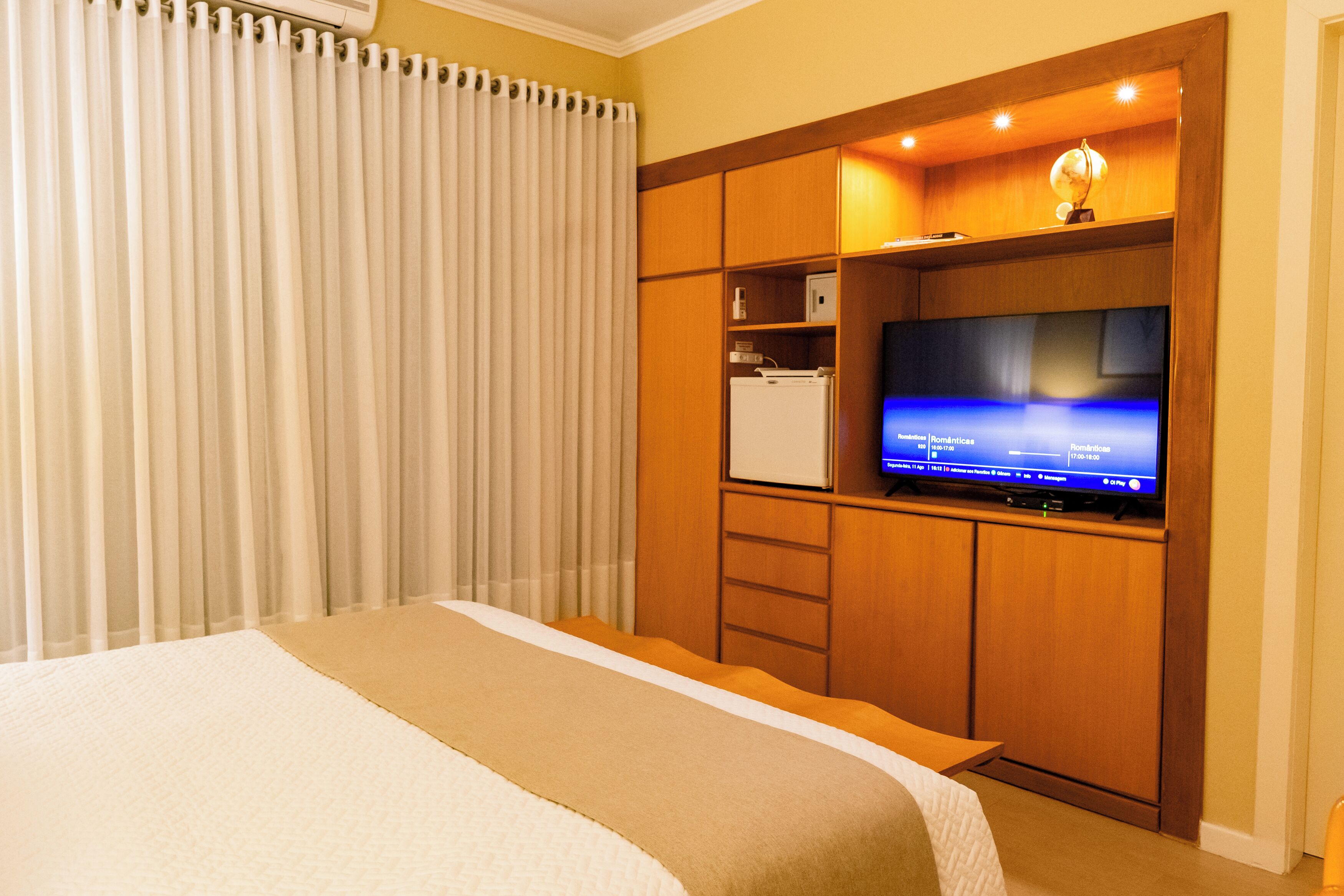 Una habitación de hotel con una cama, televisión y minibar.