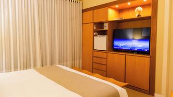 Una habitación de hotel con una cama, televisión y minibar.