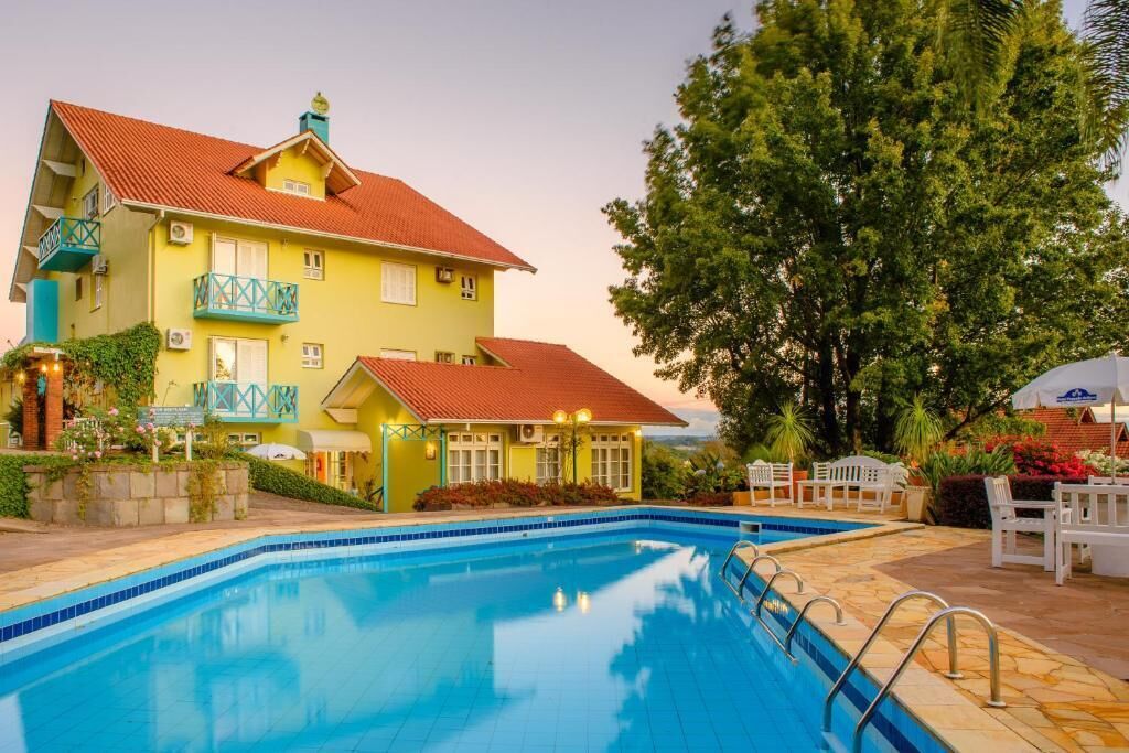 A yellow building with a red roof and a swimming pool.