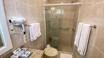 A bathroom with a hairdryer, two towels, a toilet, and a shower area.