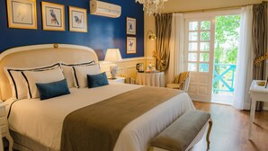 A bedroom with a large bed, bedside tables, a lamp, a chair, a small table, and a door leading to an outdoor area. - HOTEL POUSADA DA NEVE (Nova Petropolis)